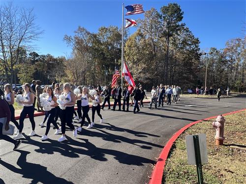 parade walking in front of Heritage Elementary led by James Clemens cheerleaders